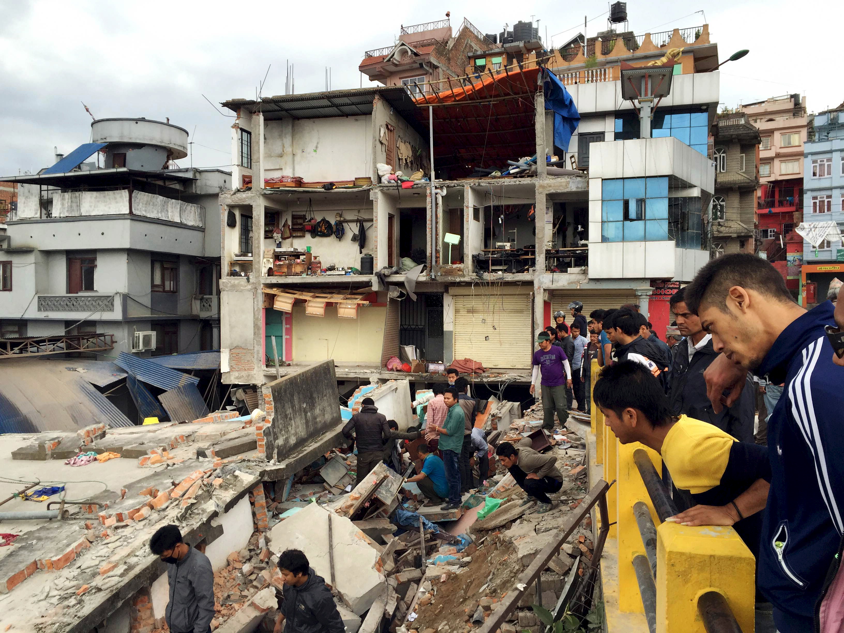 People survey a site damaged by an earthquake, in Kathmandu